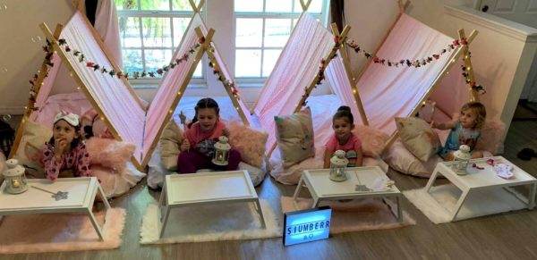 A group of girls sitting in teepee tents at a Bell Tent campsite in Lakeland.