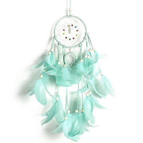 A turquoise dream catcher hanging on a white wall at a party.
