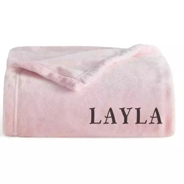 A Layla pink blanket, perfect for glamping, neatly folded with the name "layla" embossed in dark letters near the bottom edge.