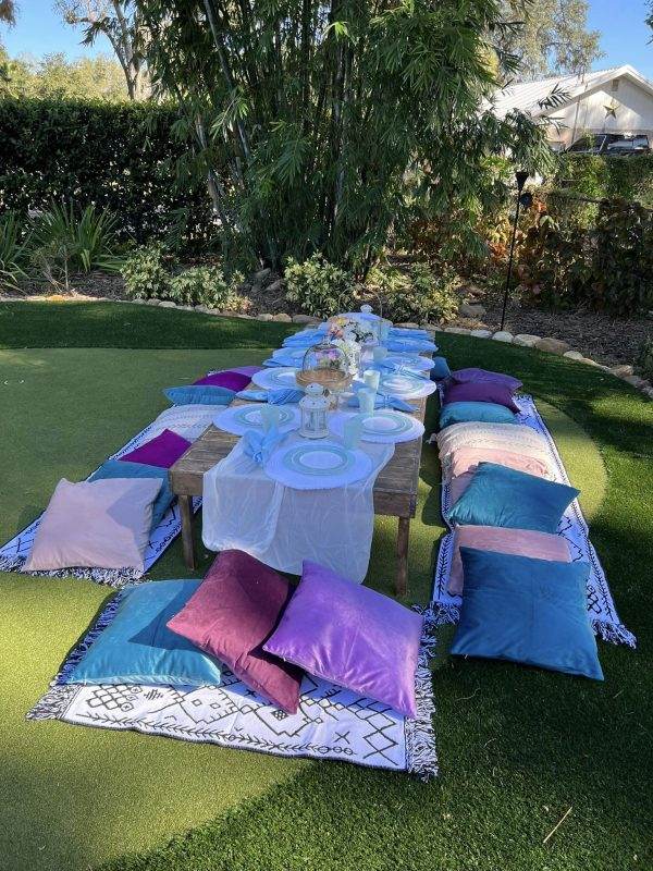Decorative custom picnic table with pillows surrounding.