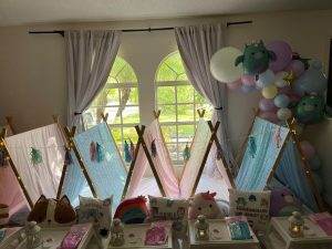 5 teepees set up inside a living room with squishmellows and party trays.