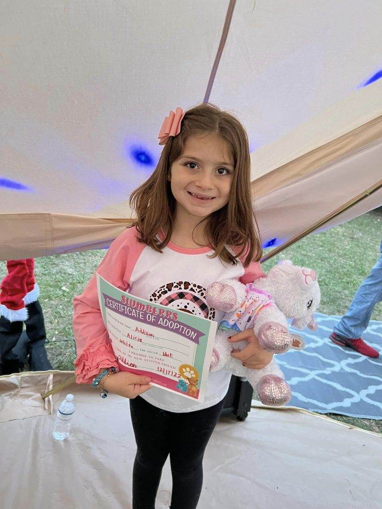 A young girl holding a certificate in front of a tent at an exciting party celebration.