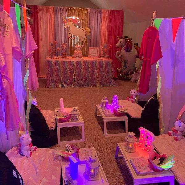 A glamping-themed room decorated for a birthday party with pink and purple decorations.