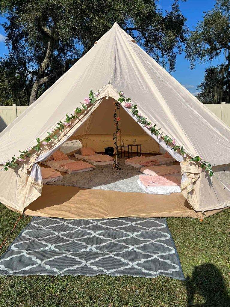 A white and pink Bell Tent with a rug on the ground.