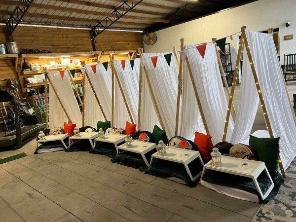 Teepee tents with tables and chairs in a warehouse.