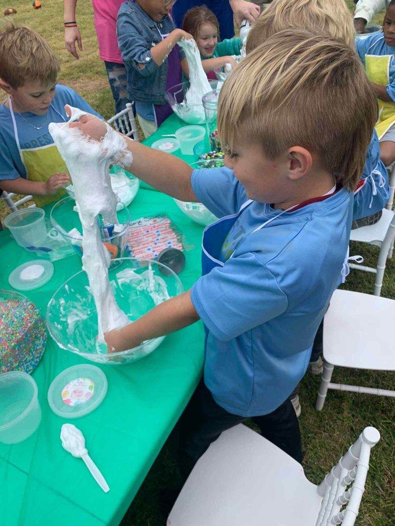 A group of children at a table party making a cake.