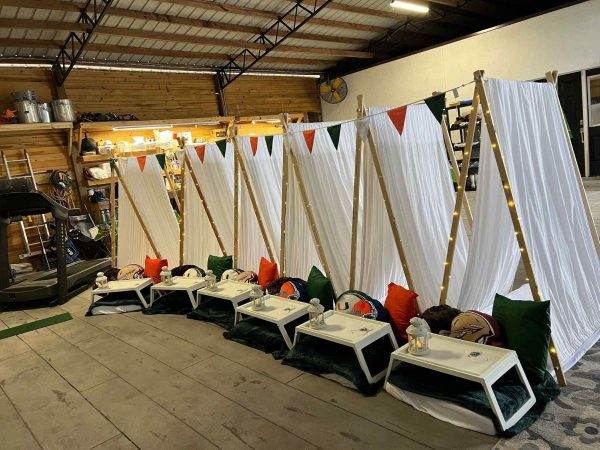 A row of Bell Tents and tables in a warehouse for a Glamping party.