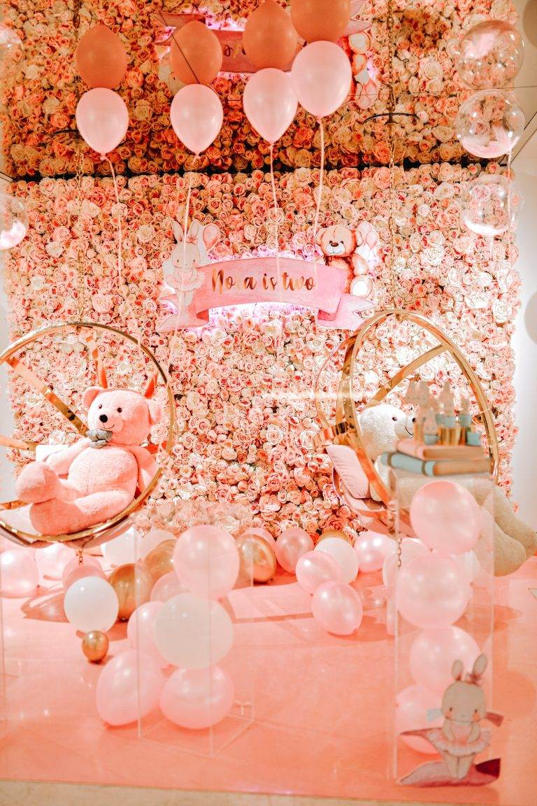 A pink and white party with balloons, teddy bears, and a teepee.