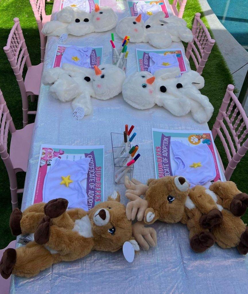 If you are looking for a way to entertain the kids during a wedding this picture of a long 6ft table and chairs pictures in the photo includes build a bear party materials next to birth certificates.