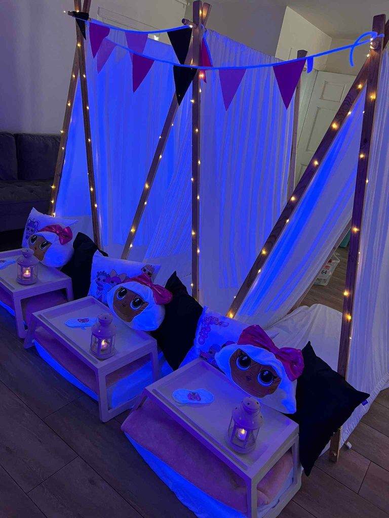 A Bell Tent transformed into a glamping party oasis, adorned with blue lights and surrounded by an array of whimsical stuffed animals.