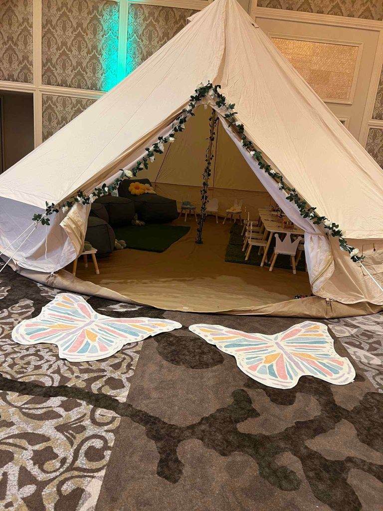 A white tent adorned with delicate butterflies on the floor, perfect for a serene and enchanting glamping experience in Lakeland.