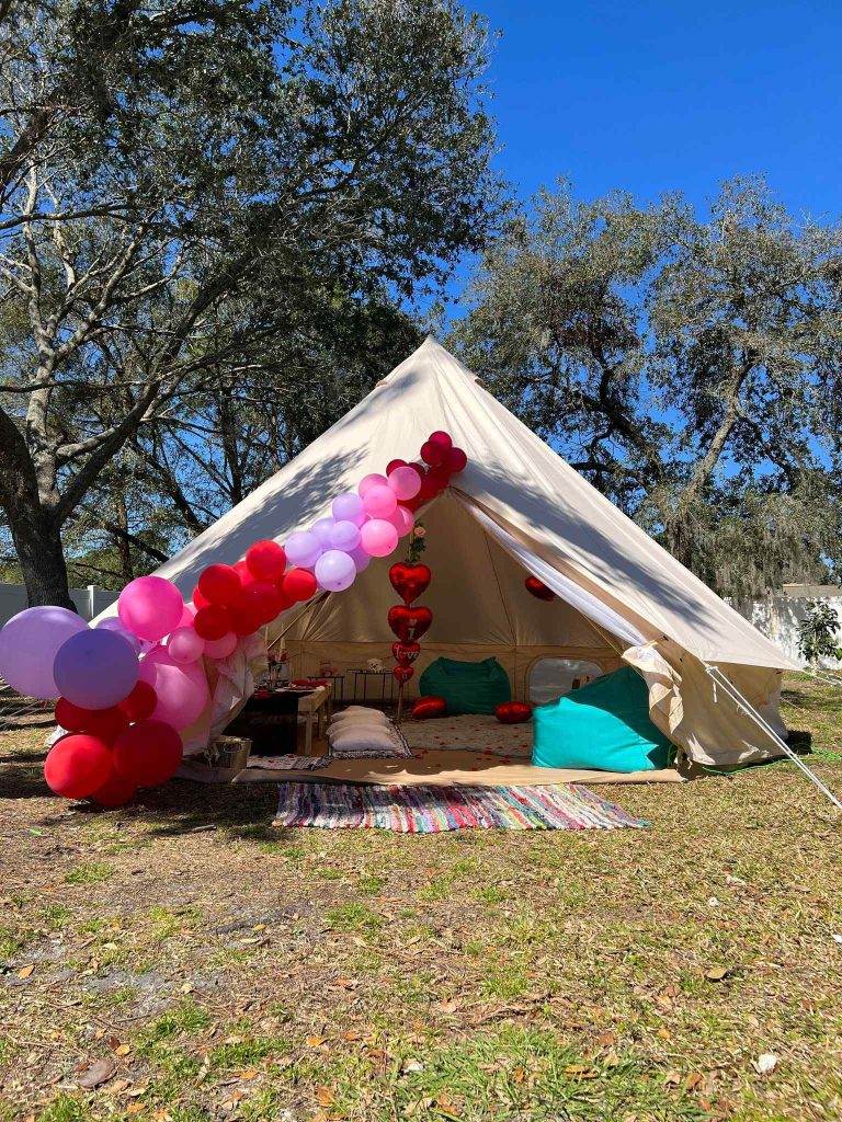 Bell tent rental and balloon garland tied to the entry from Slumberr