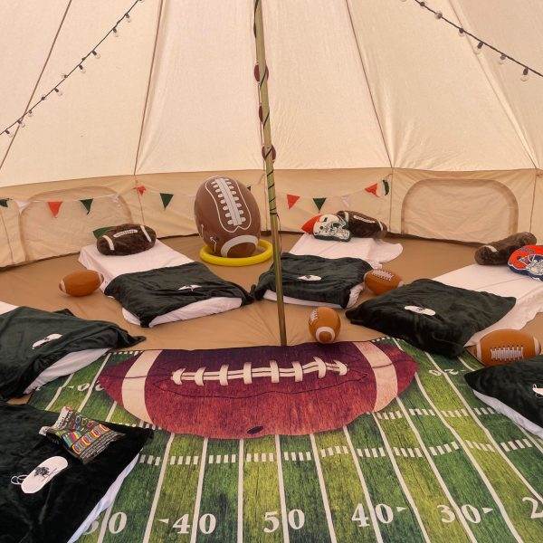 Photo of inside a Football themed bell tent. Football blankets and pillows with football field rug