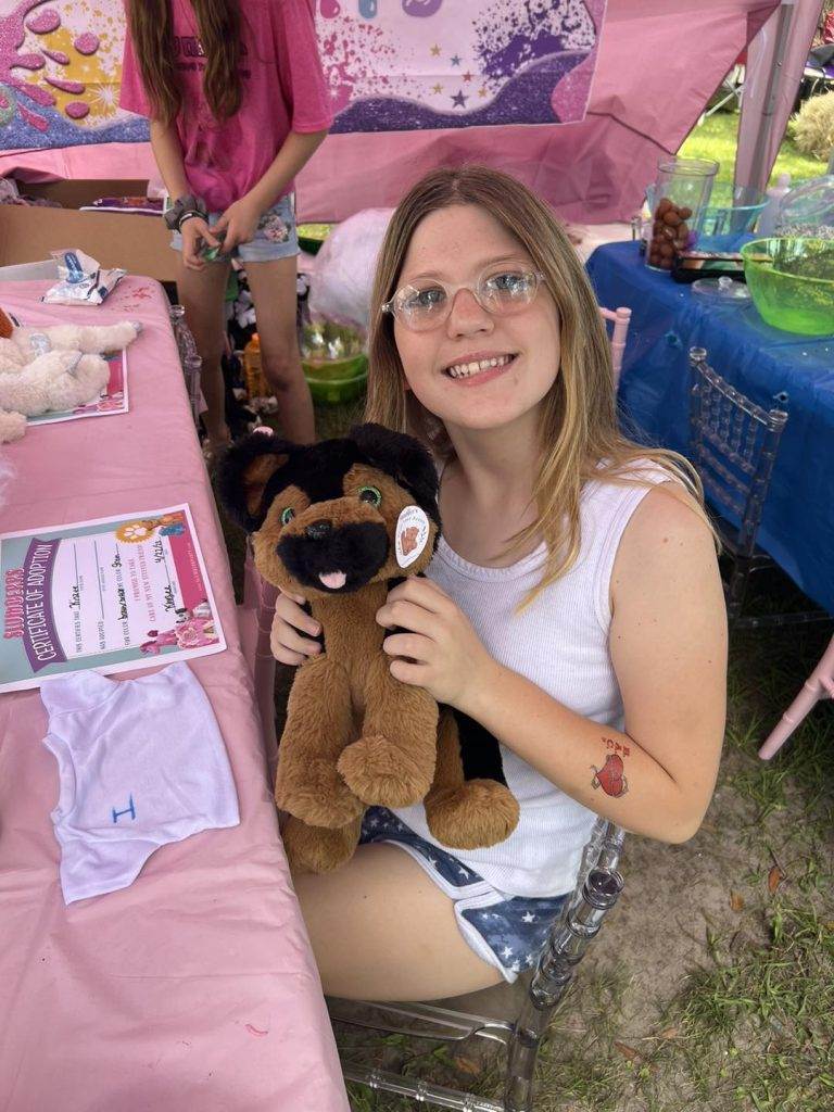 A Lakeland girl holding a stuffed animal at a party.