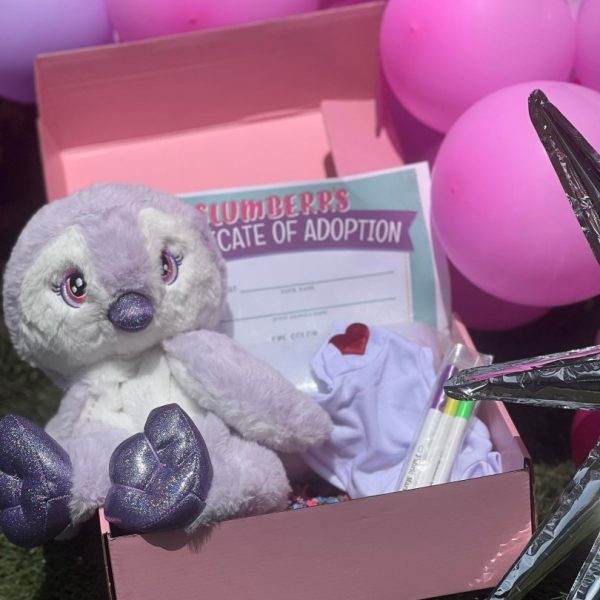 A pink Slime Party Box with a stuffed animal and balloons for a party.