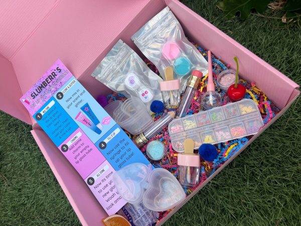 A pink box filled with DIY Lip Gloss Party Box and other items, including a bell tent.