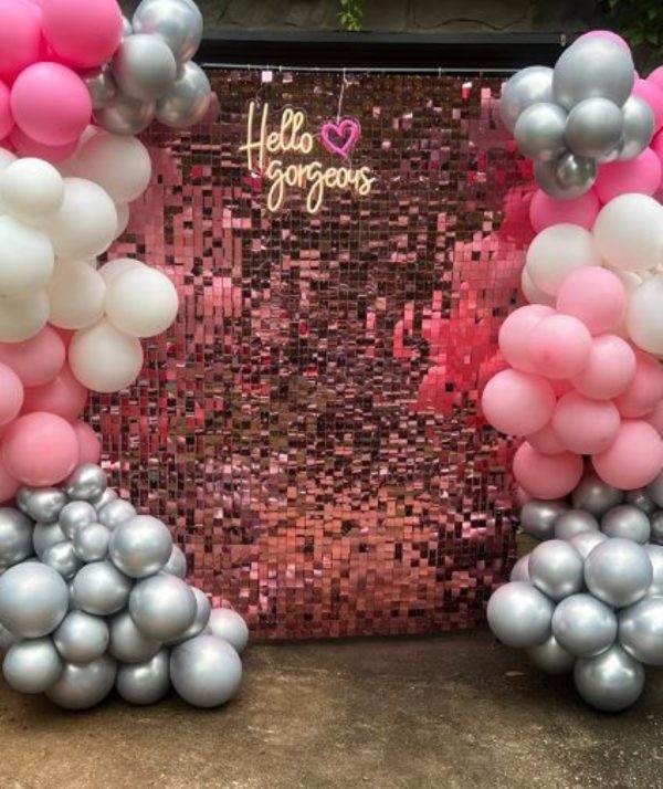 A party photo booth adorned with pink and silver balloons.