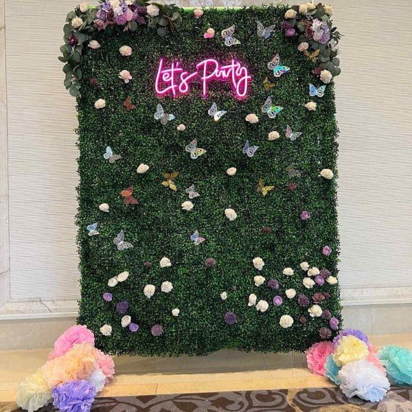 A green wall with flowers and a sign that says life party.