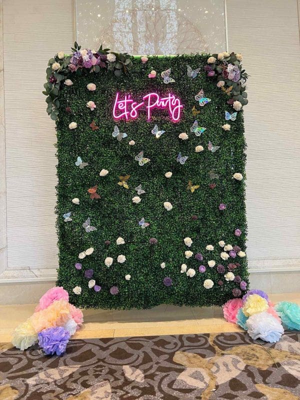 A green wall with flowers and a sign that says life party.