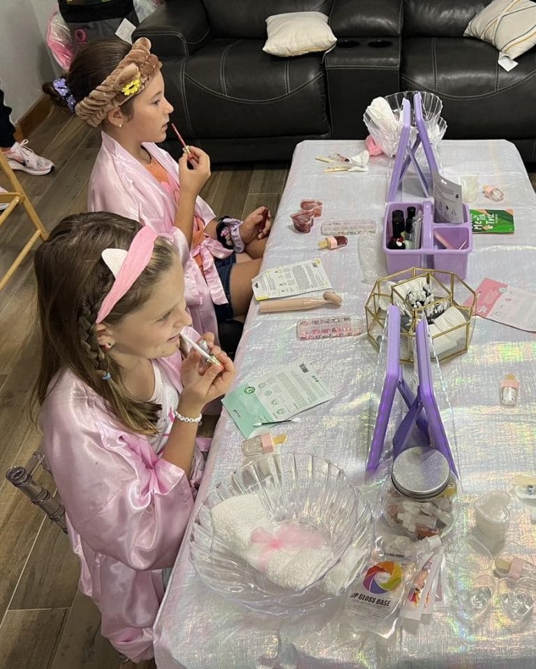 A group of girls are having a slime party at a table in a living room.