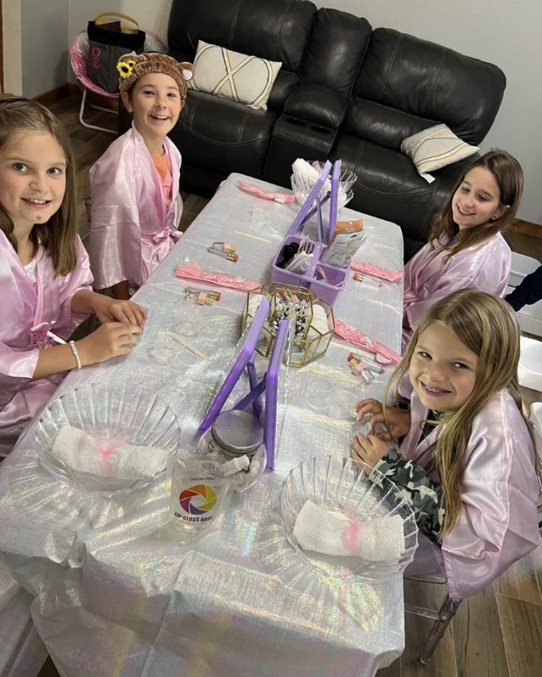 A group of girls in pink robes, gathered around a table covered with slime.