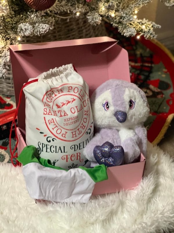 A Holiday Build-A-Bear Party Box next to a Christmas tree.