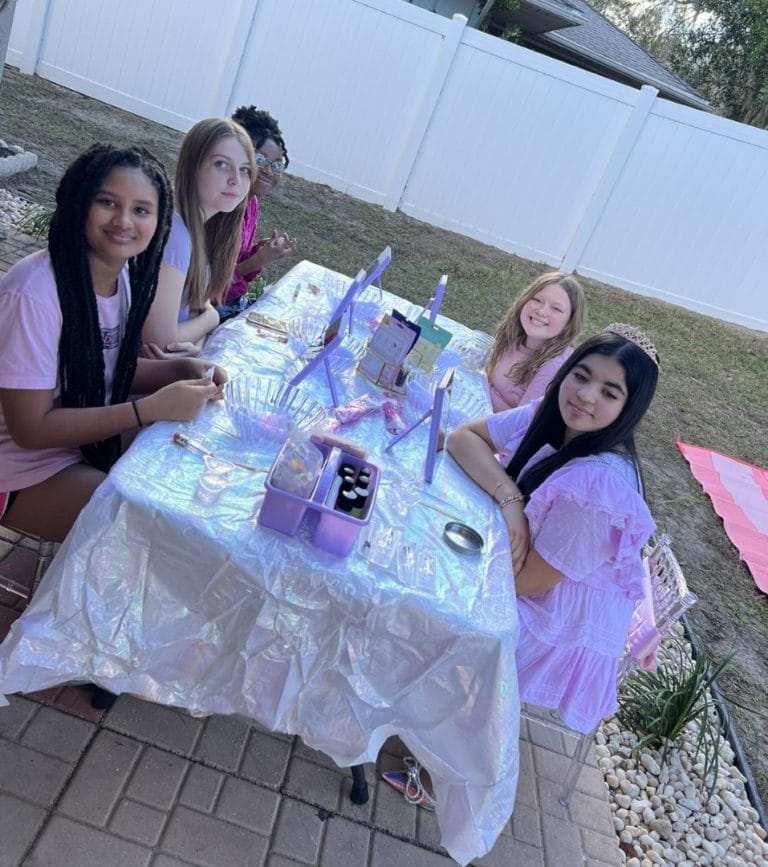 A group of girls sitting at a table in a Lakeland backyard party.