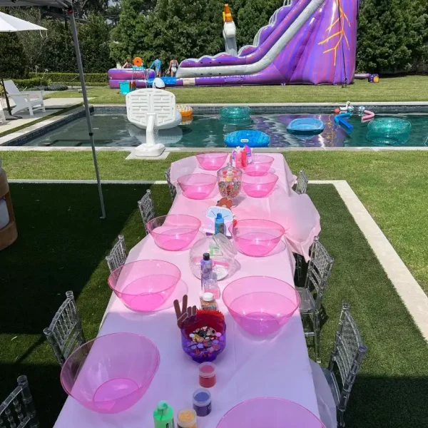 A table set up for a slime making party with a water slide, perfect for pink-themed celebrations in Lakeland, orlando, Tampa, Miami and surrounding areas.