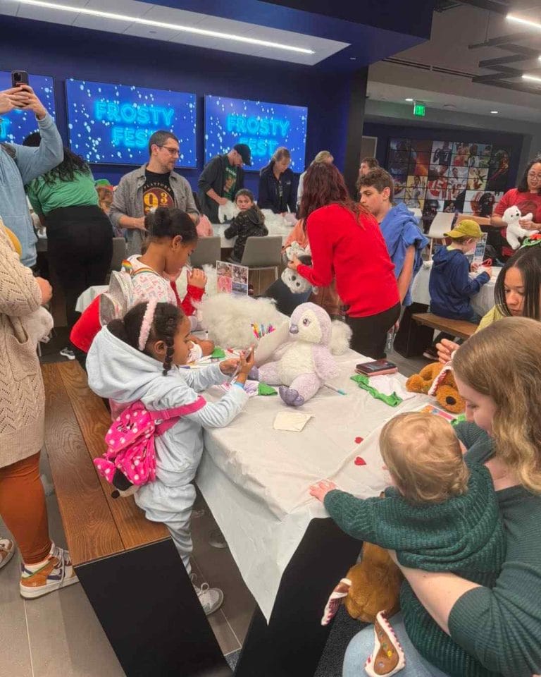 A group of children having a party at a table with stuffed animals.