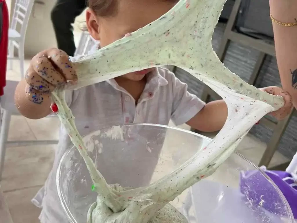 A child is playing with a bowl of sand at a party.