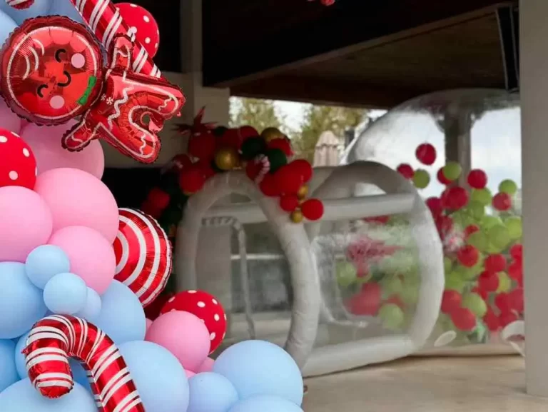 A group of balloons decorated with candy canes and candy canes, surrounding an inflatable bubble bounce house