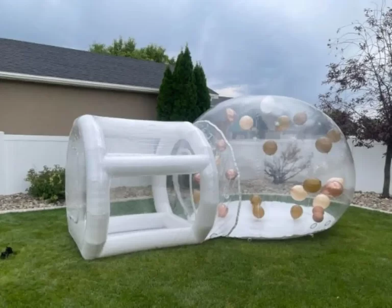 Inflatable transparent bubble tent with tunnel entrance in a backyard.