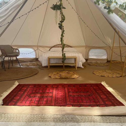 A Lakeland Bell Tent ideal for glamping, featuring a cozy rug in the middle.